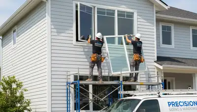 Technician repairing window frame with vinyl siding in Fort Collins CO home exterior